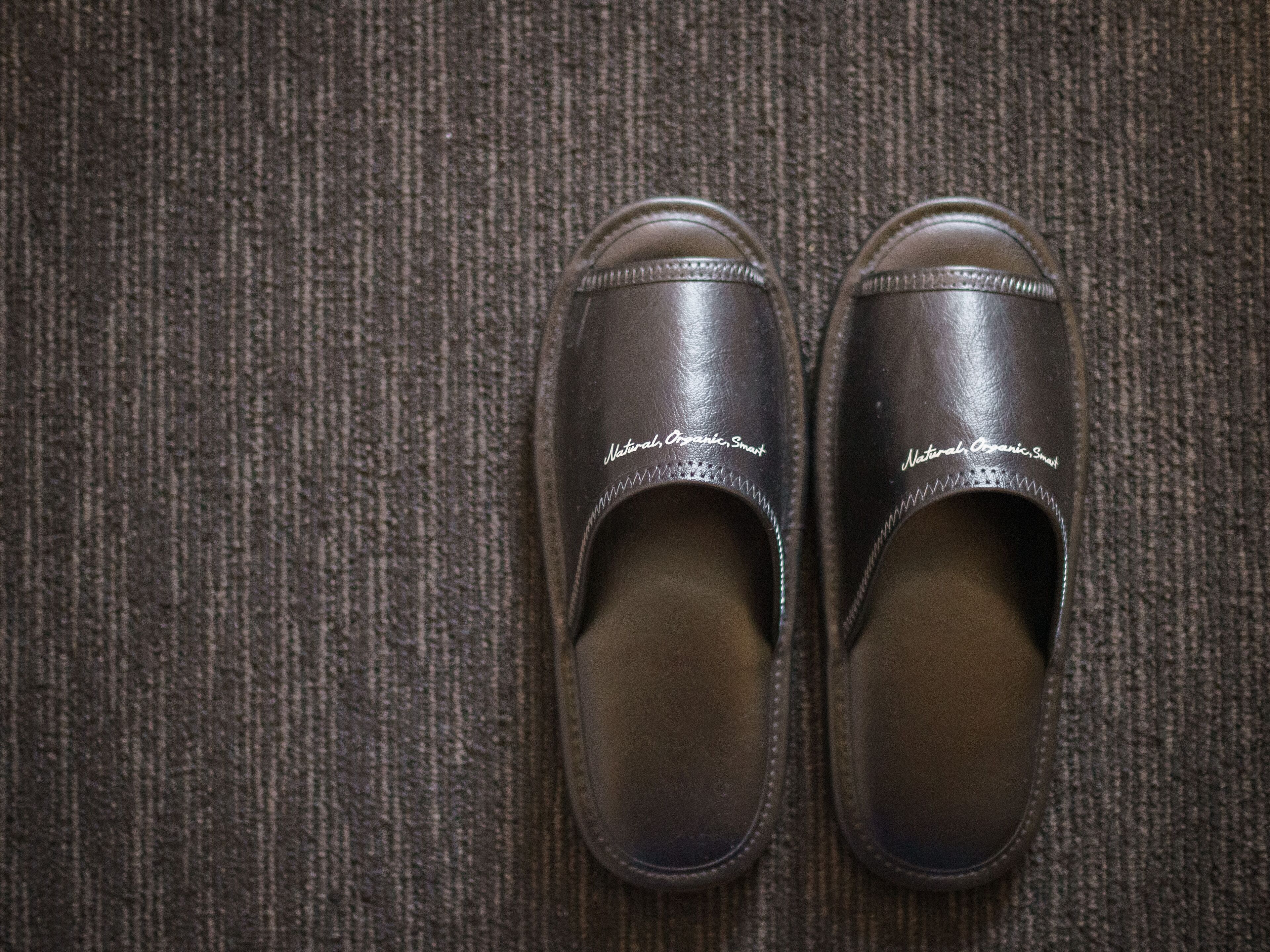 A pair of brown shoes with white text on the side, placed on a textured surface.