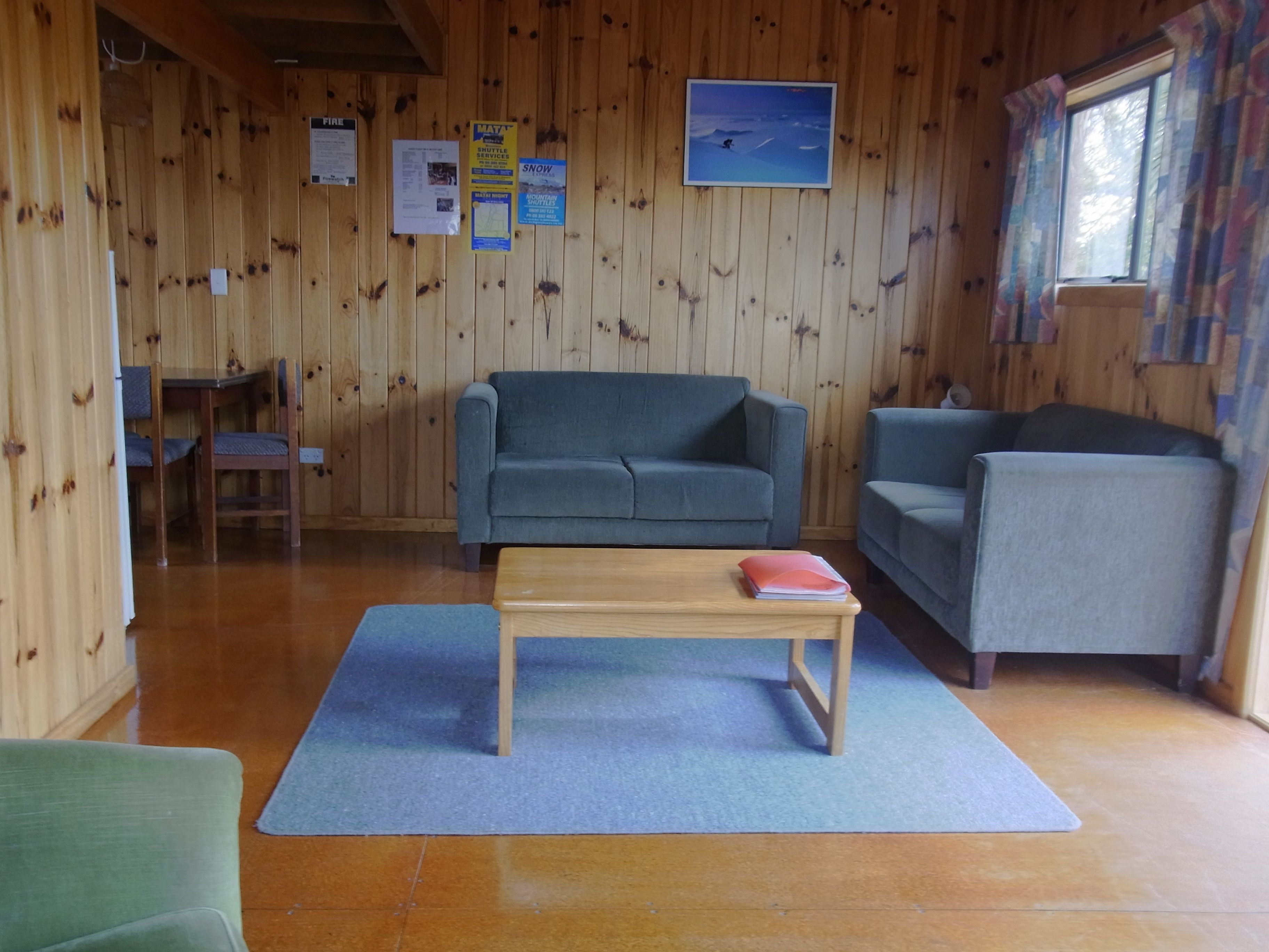 Een houten interieur met een bank, fauteuil en een klein tafeltje met een notitieboekje.