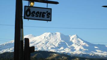 A sign for Ossie's with a mountain in the background.