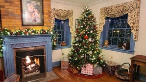 Una habitació acollidora amb una llar de foc, un arbre de Nadal decorat i una finestra amb cortines.