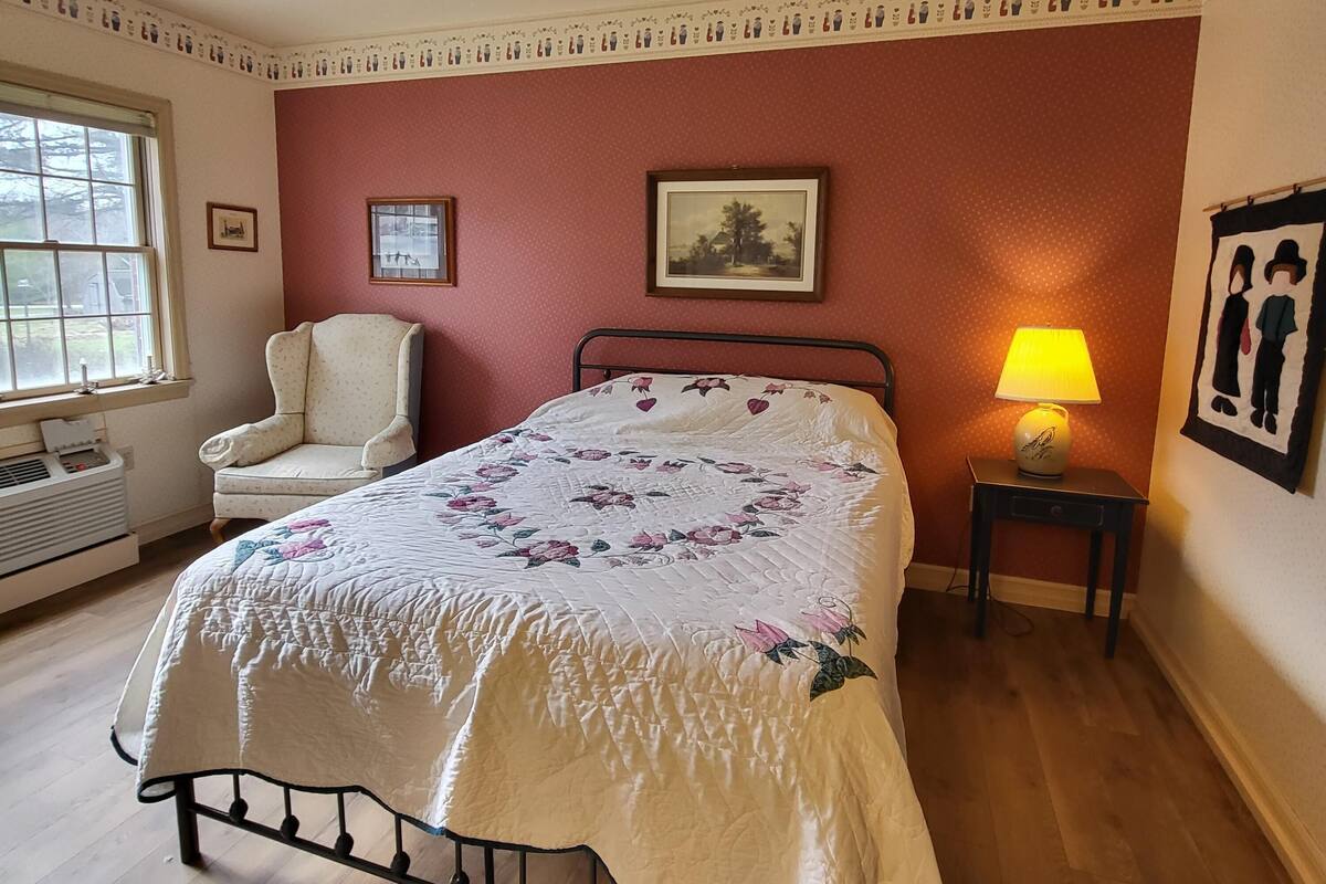 A bedroom with a bed, a chair, a lamp, and a picture on the wall.