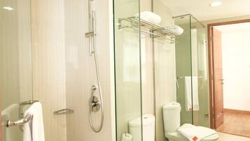 Un baño moderno con ducha de vidrio, inodoro y puerta de vidrio que da a otra habitación.