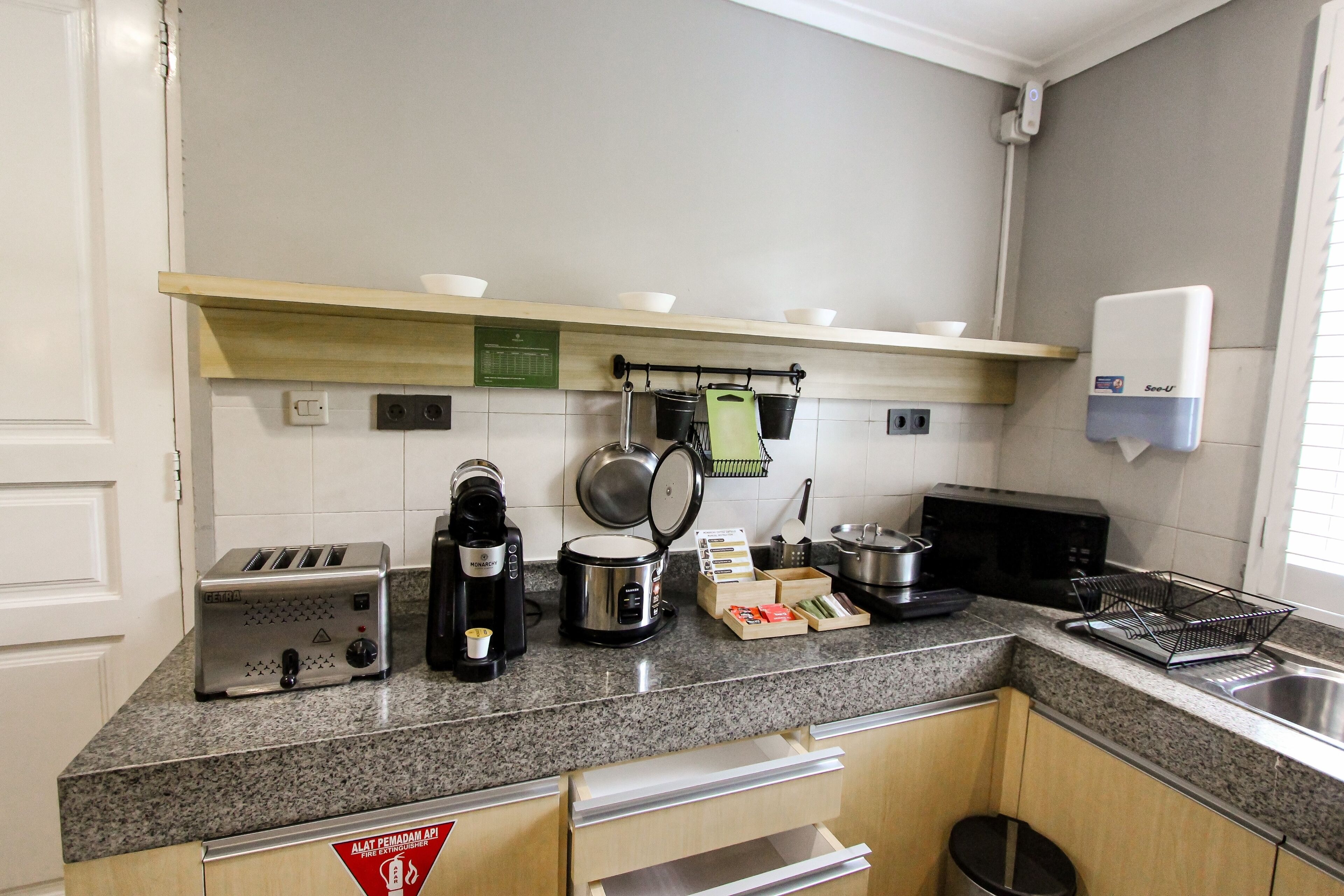 A kitchen with granite countertops, a toaster, a coffee maker, a microwave, and a sink.
