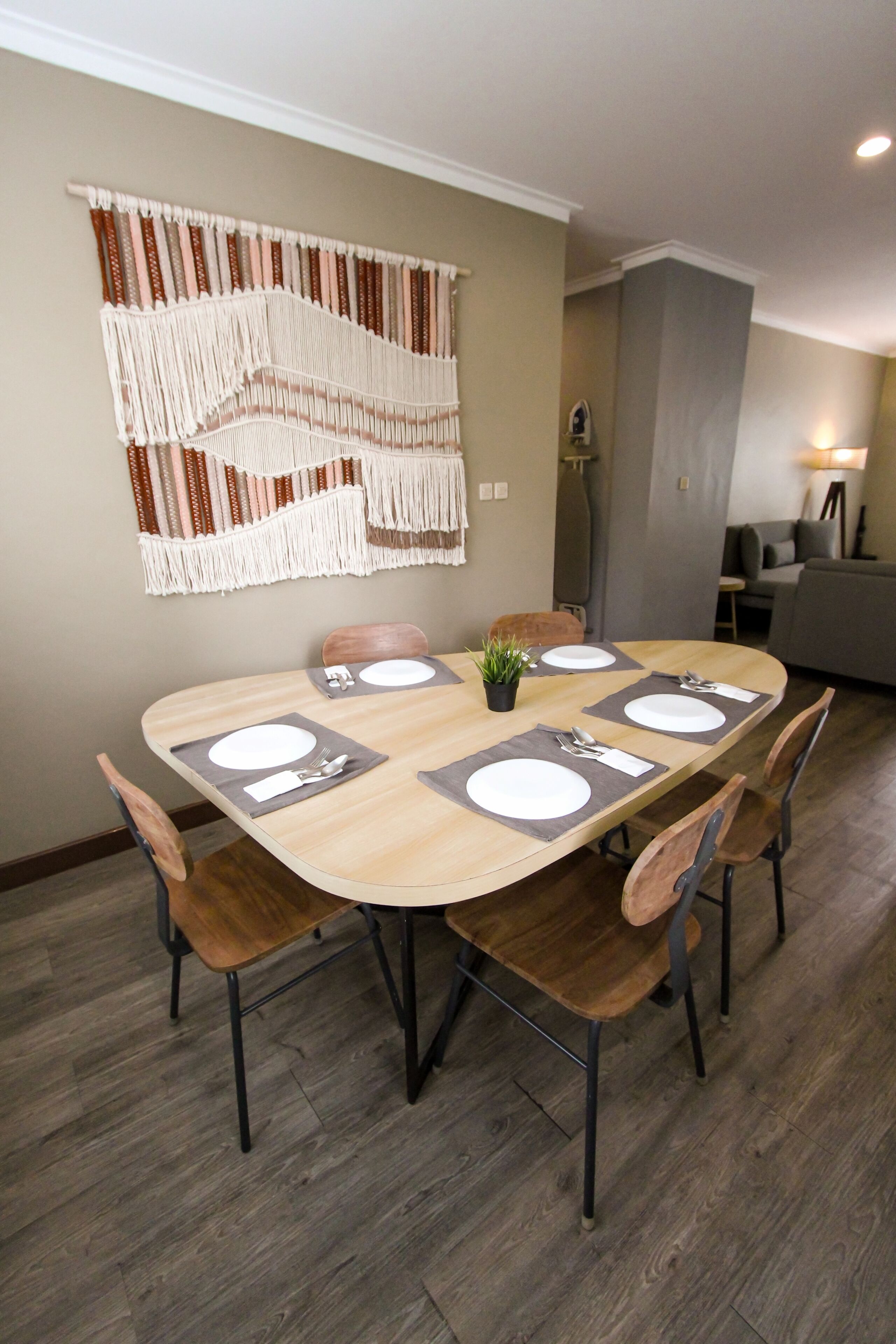 A dining area with a wooden table set for six, surrounded by chairs.