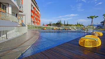 Relax by the spacious outdoor pool with a wooden deck and wicker lounge chairs.