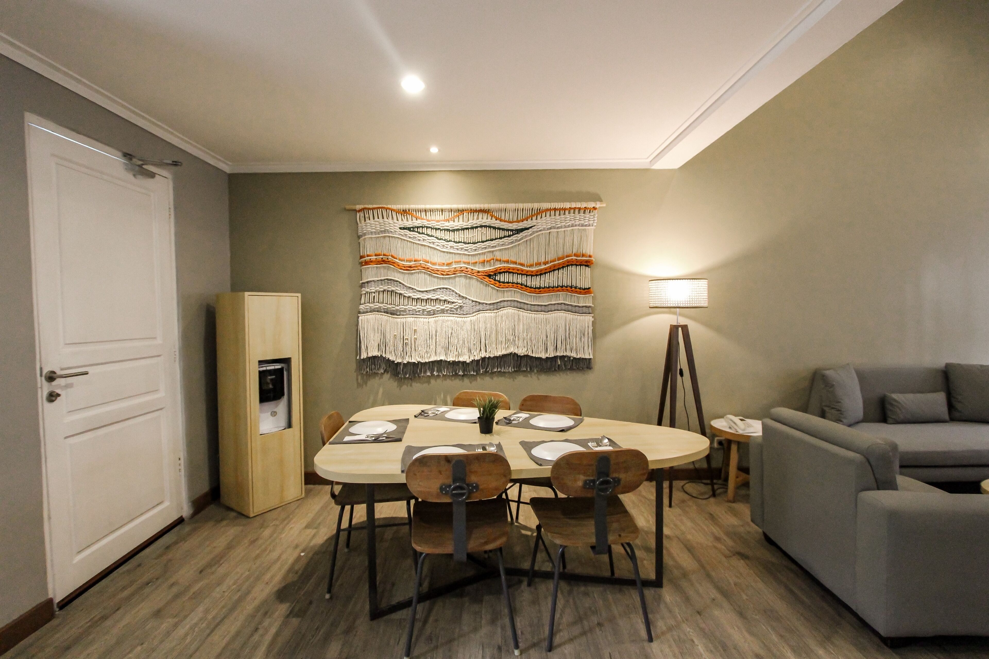 Un coin repas comprenant une table ronde, des chaises, une tapisserie murale, un canapé et une lampe.