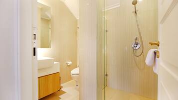A modern bathroom with a glass-enclosed shower, a toilet, and a sink.