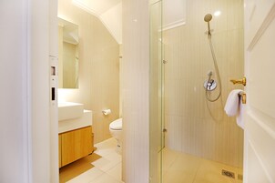 A modern bathroom with a glass-enclosed shower, a toilet, and a sink.