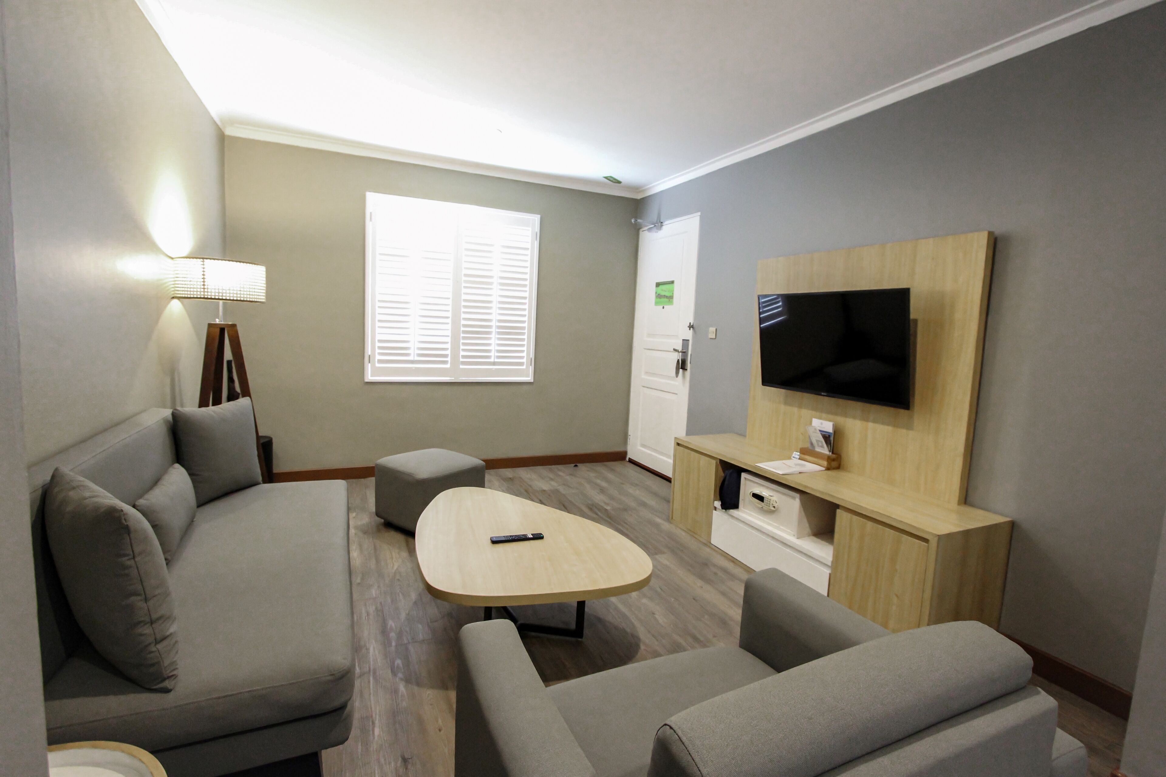 A modern living room with a sofa, a coffee table, and a TV mounted on the wall.