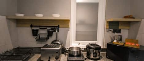 Una cocina con tostadora, hervidor y cafetera sobre la encimera.