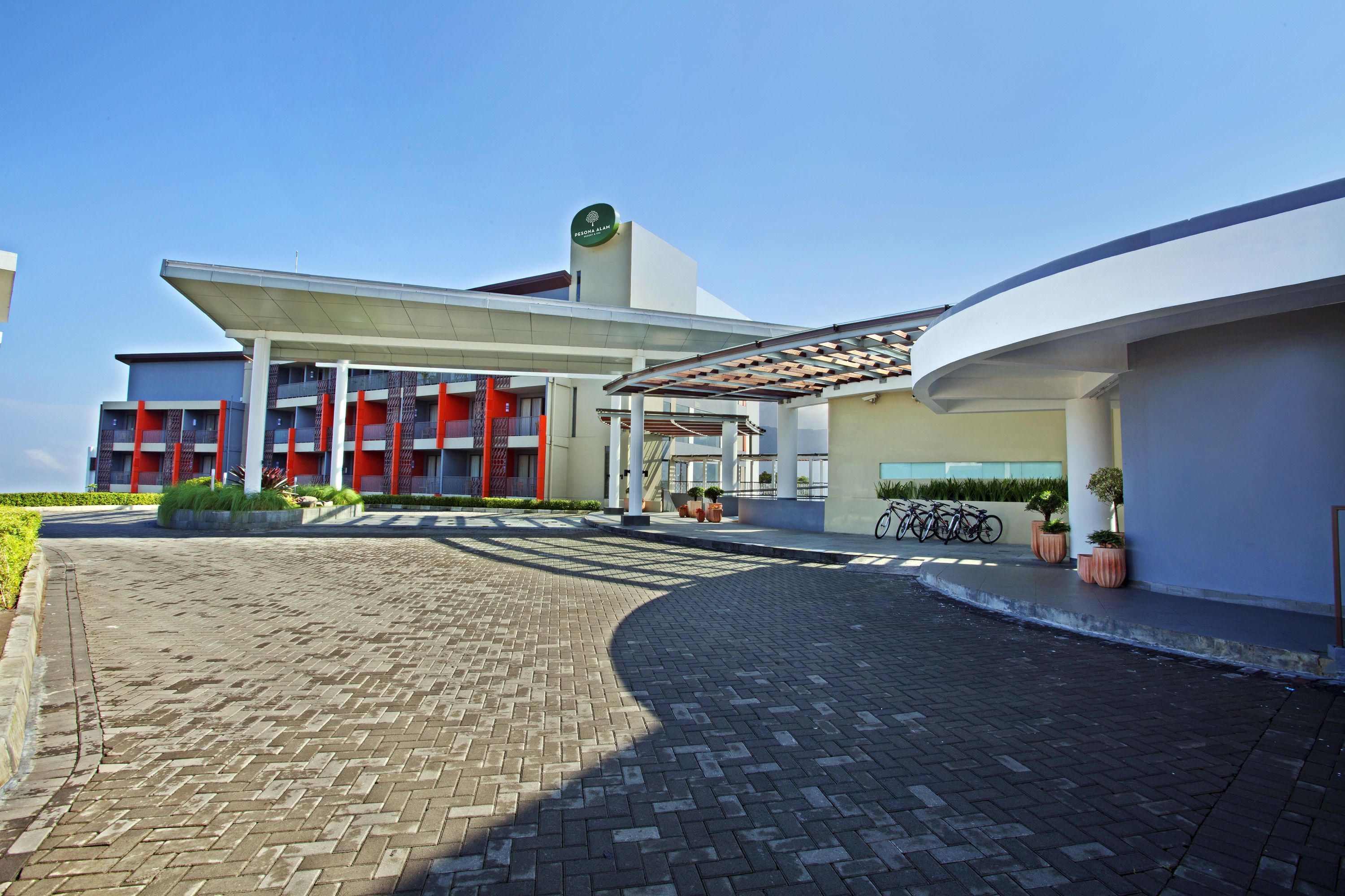 A modern building with a covered entrance, a clear sky, and a paved driveway.