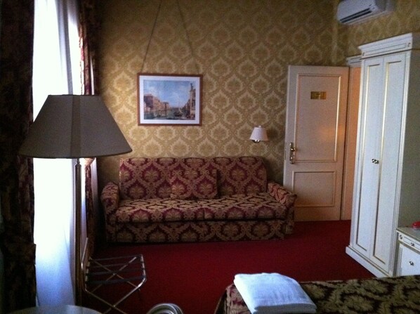 A room with a patterned sofa, a lamp, a wardrobe, and a framed picture on the wall. - Casa Arte (Venice)