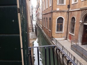 A narrow canal flanked by historic buildings with arched windows and a metal railing along the edge. - Casa Arte (Venice)