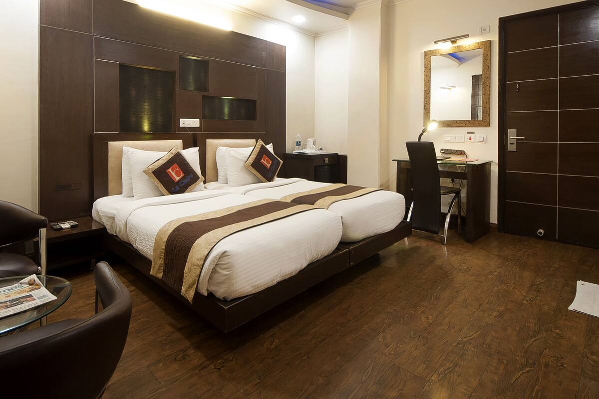 A hotel room with a large bed, a desk, a chair, and a wardrobe.