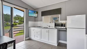 A modern kitchen with white cabinets, a microwave, and a refrigerator. - Yandina Caravan Park (Sunshine Coast)