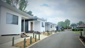 A row of modern, single-story mobile homes with a paved driveway and minimal landscaping. - Yandina Caravan Park (Sunshine Coast)