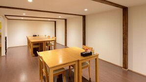 A conference room with wooden tables and chairs, a black box with items on the table, and wooden beams on the ceiling.