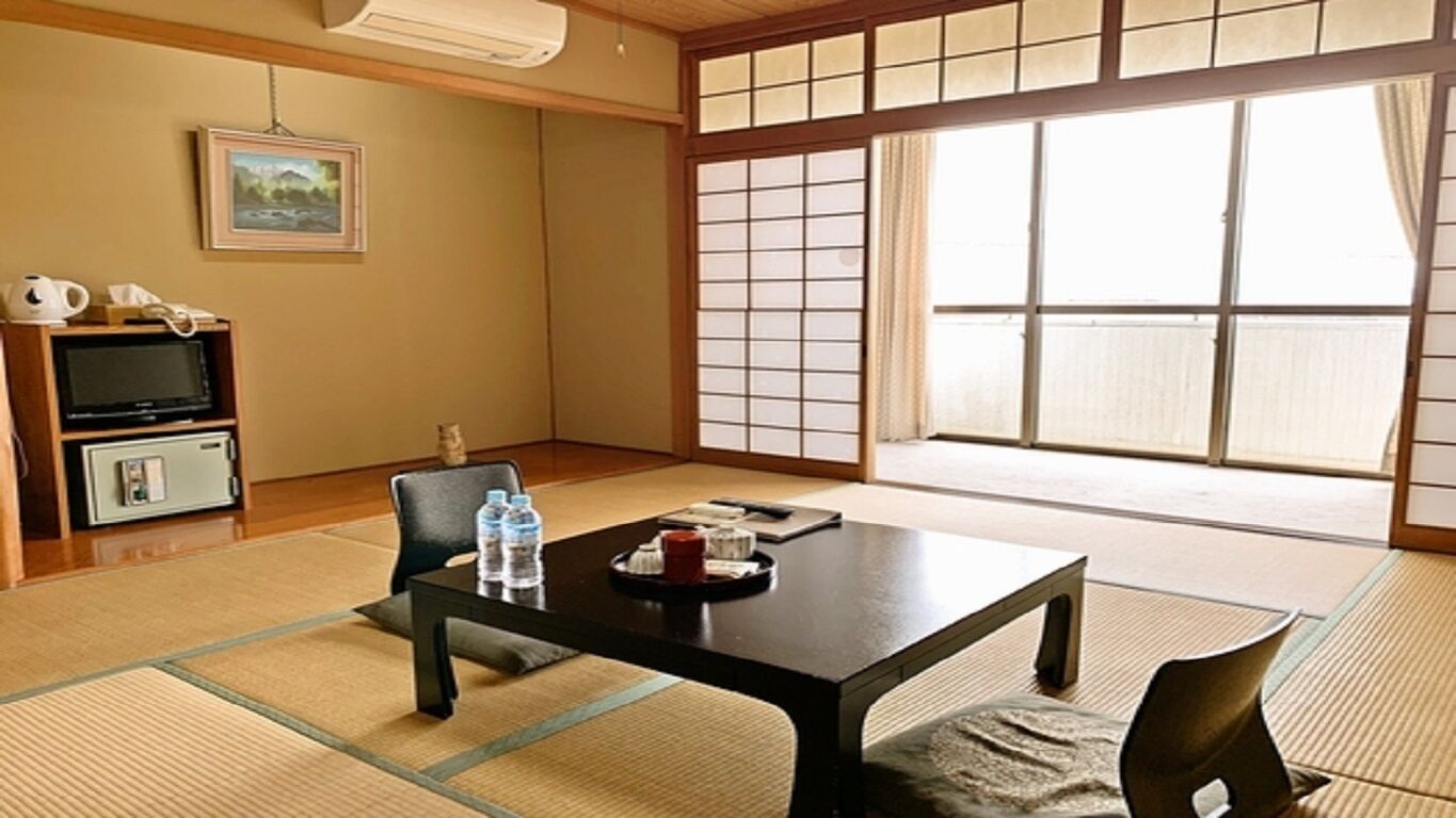 A traditional Japanese room with tatami flooring, a low table, and a sliding door.