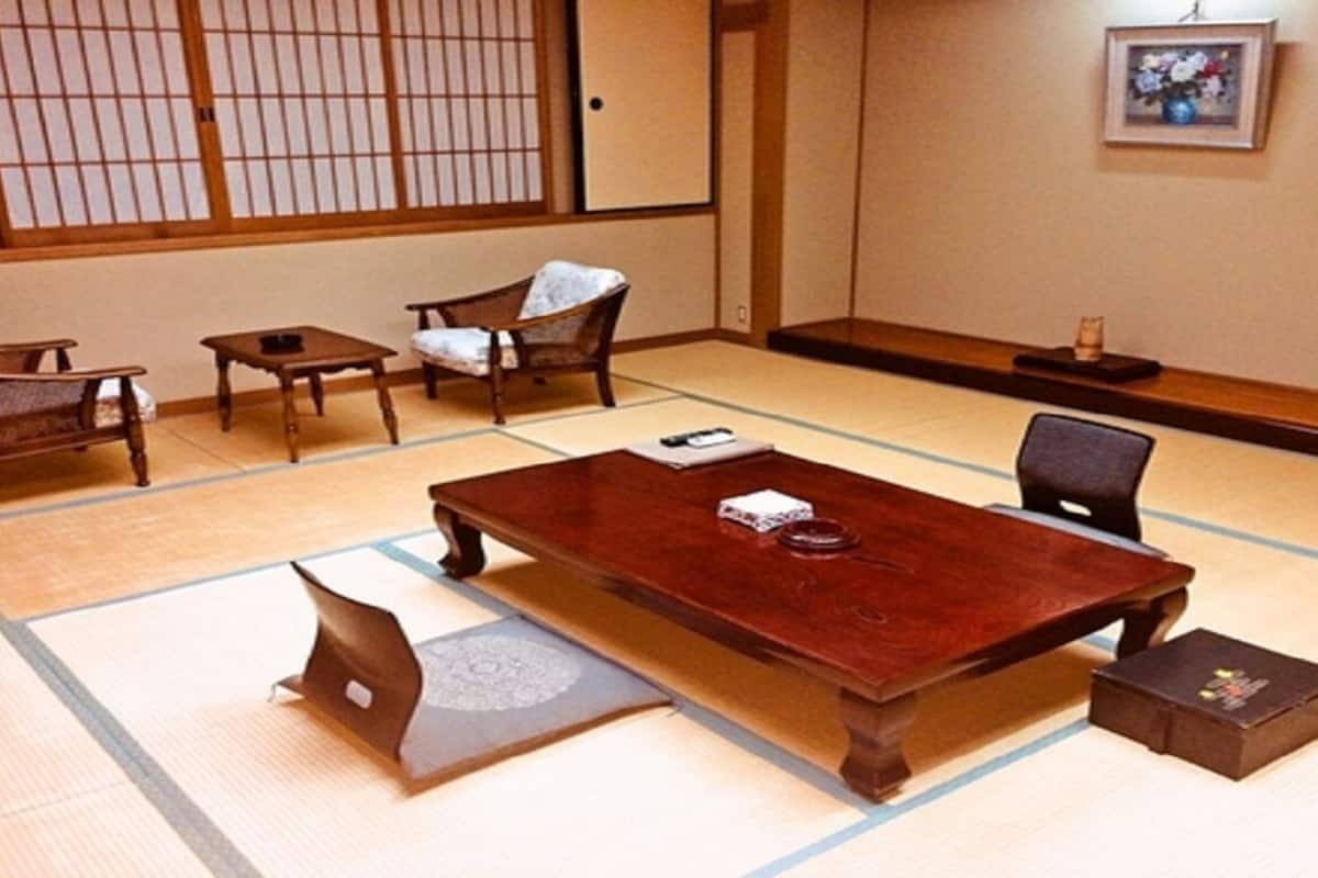 A traditional Japanese room with tatami flooring, a wooden table, chairs, and a shoji screen.