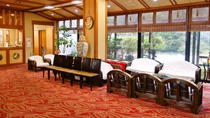 A traditional Japanese-style room with tatami mats, wooden furniture, and large windows offering a view of greenery. - Hamasaka Onsen Totoya (Shinonsen)