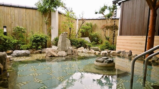 A traditional Japanese garden with a stone pond, wooden fence, and various plants. - Hamasaka Onsen Totoya (Shinonsen)