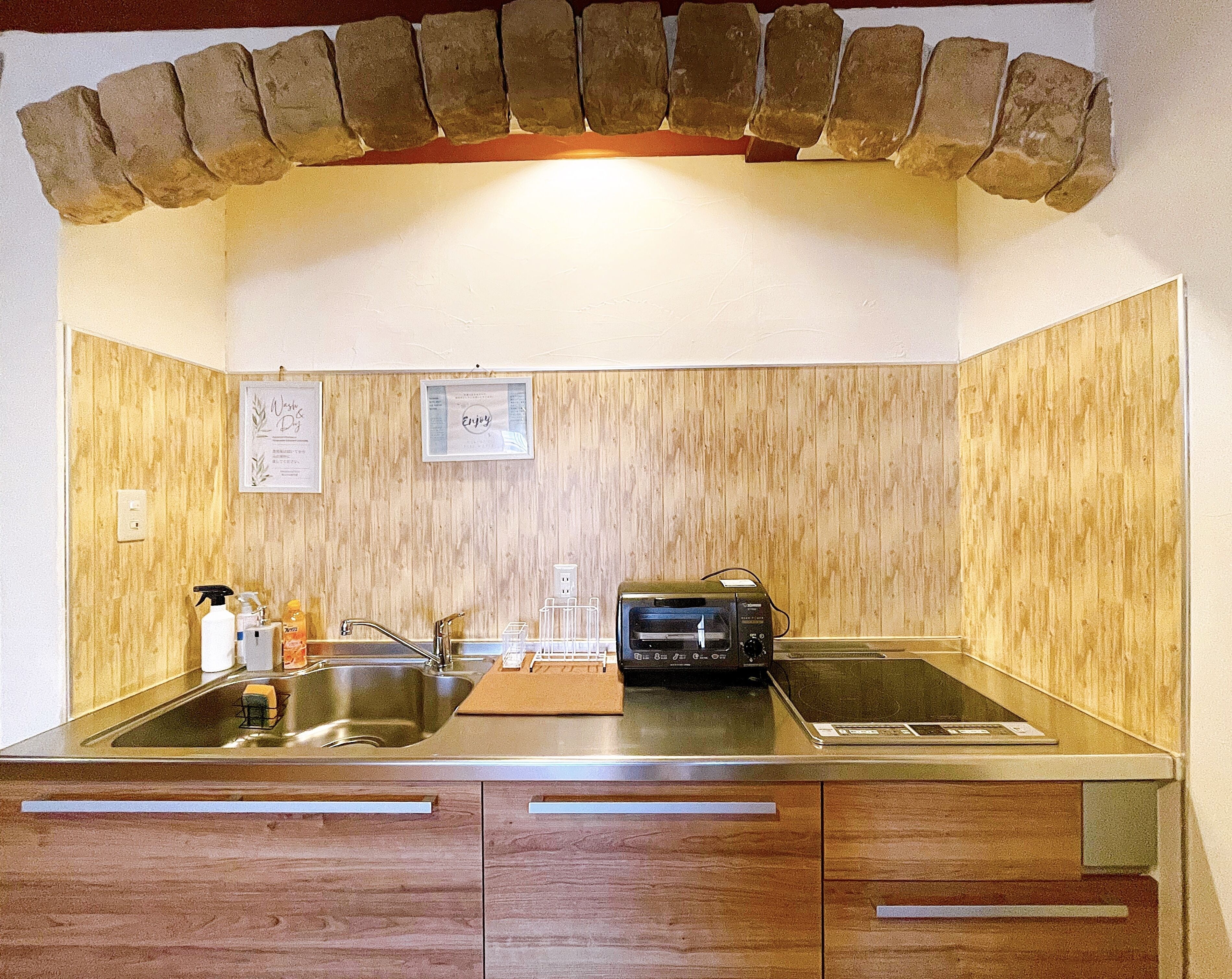 A kitchen with wooden panel walls, a built-in stove, a sink, and a countertop.