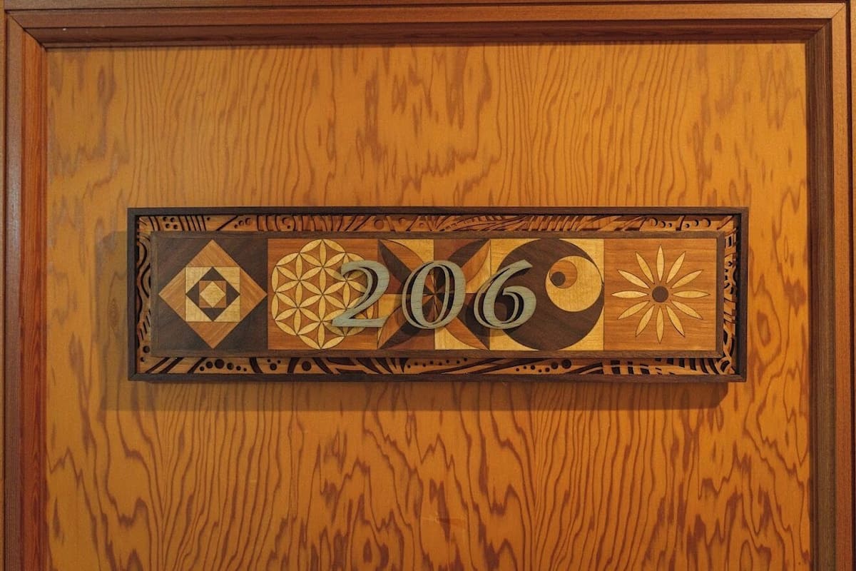 A wooden door with a decorative plaque featuring geometric patterns and the number '206'.