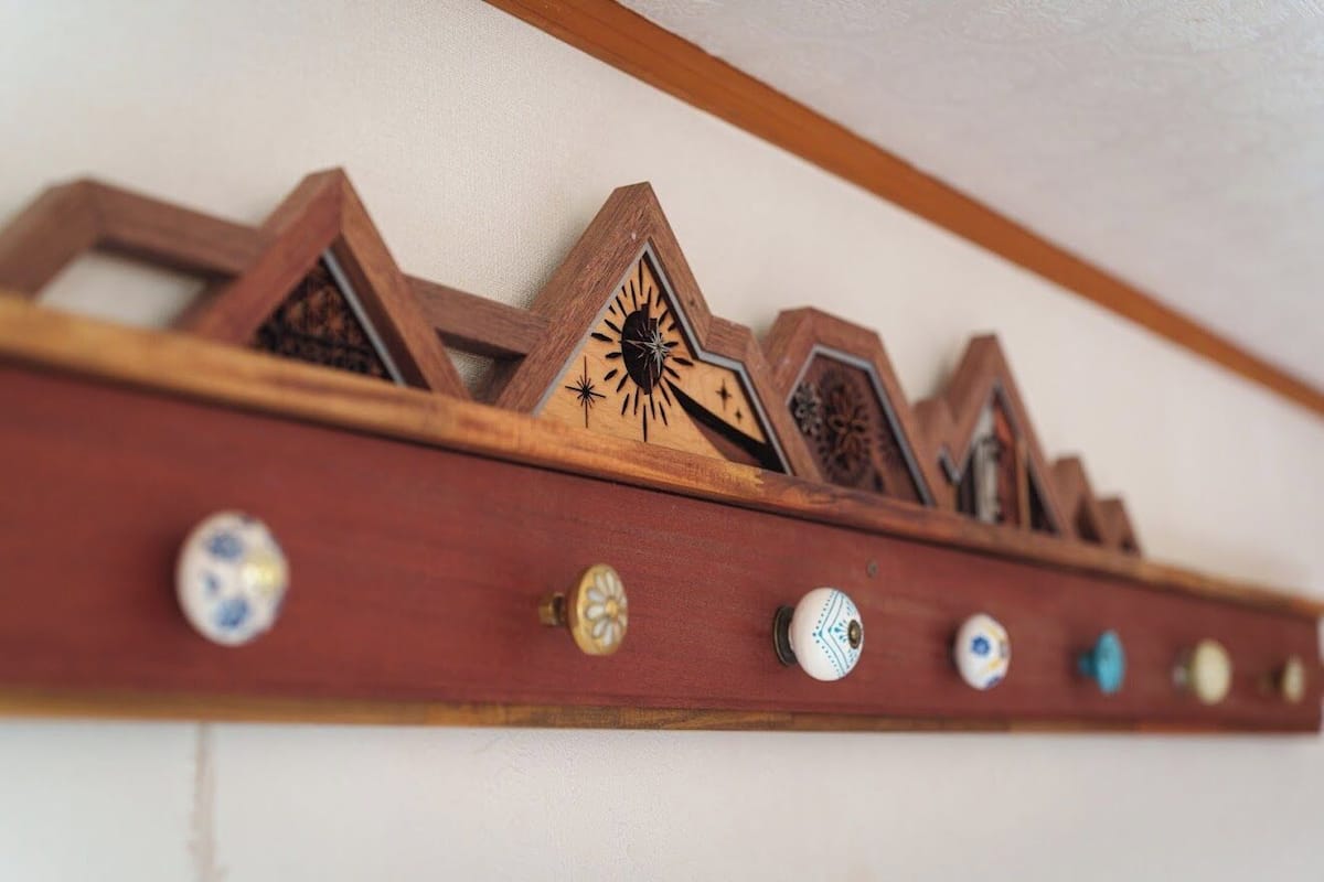 A wooden shelf with decorative wooden triangles and a row of knobs.