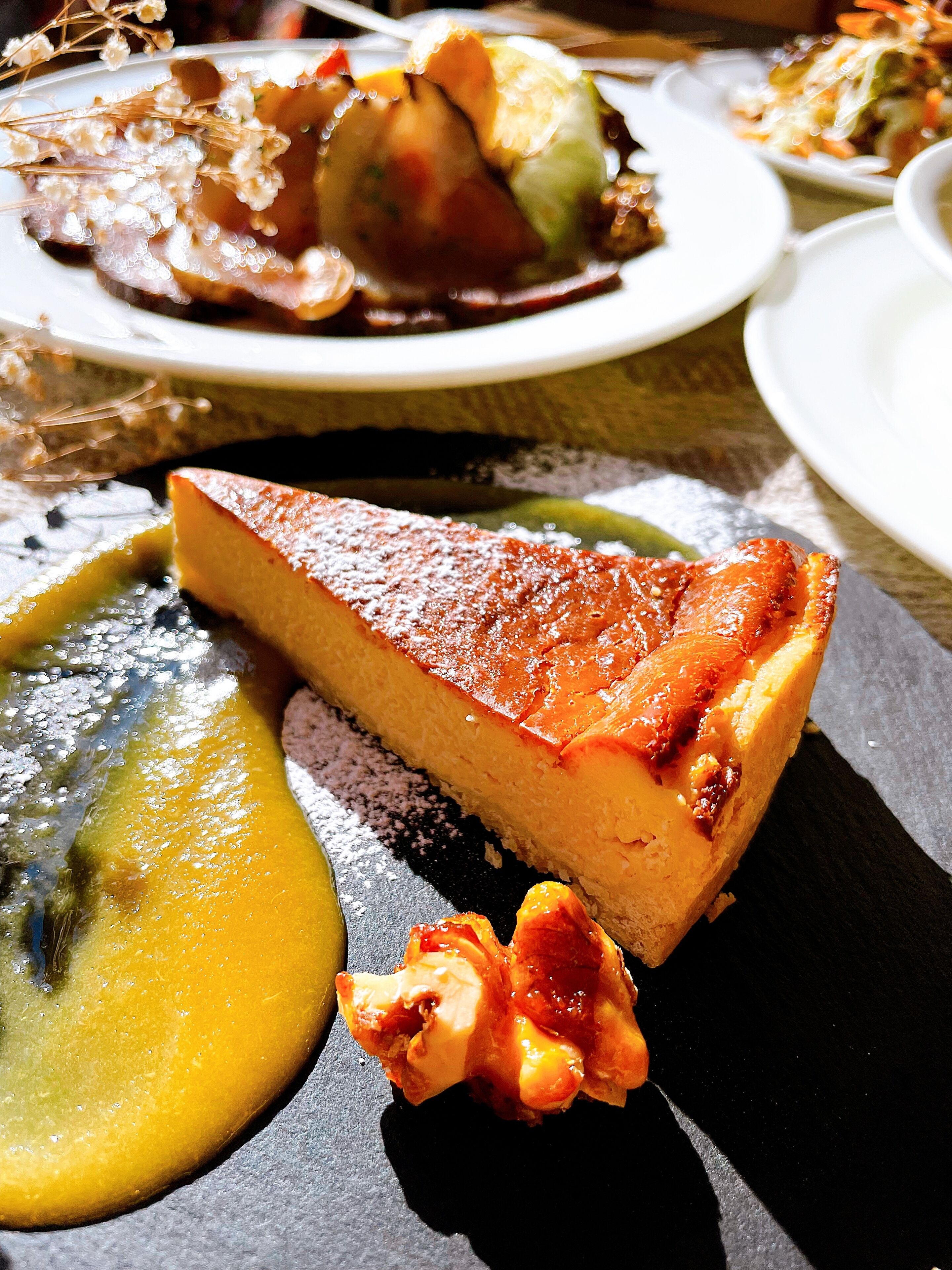 A dessert plate with a slice of cheesecake and a fruit sauce.