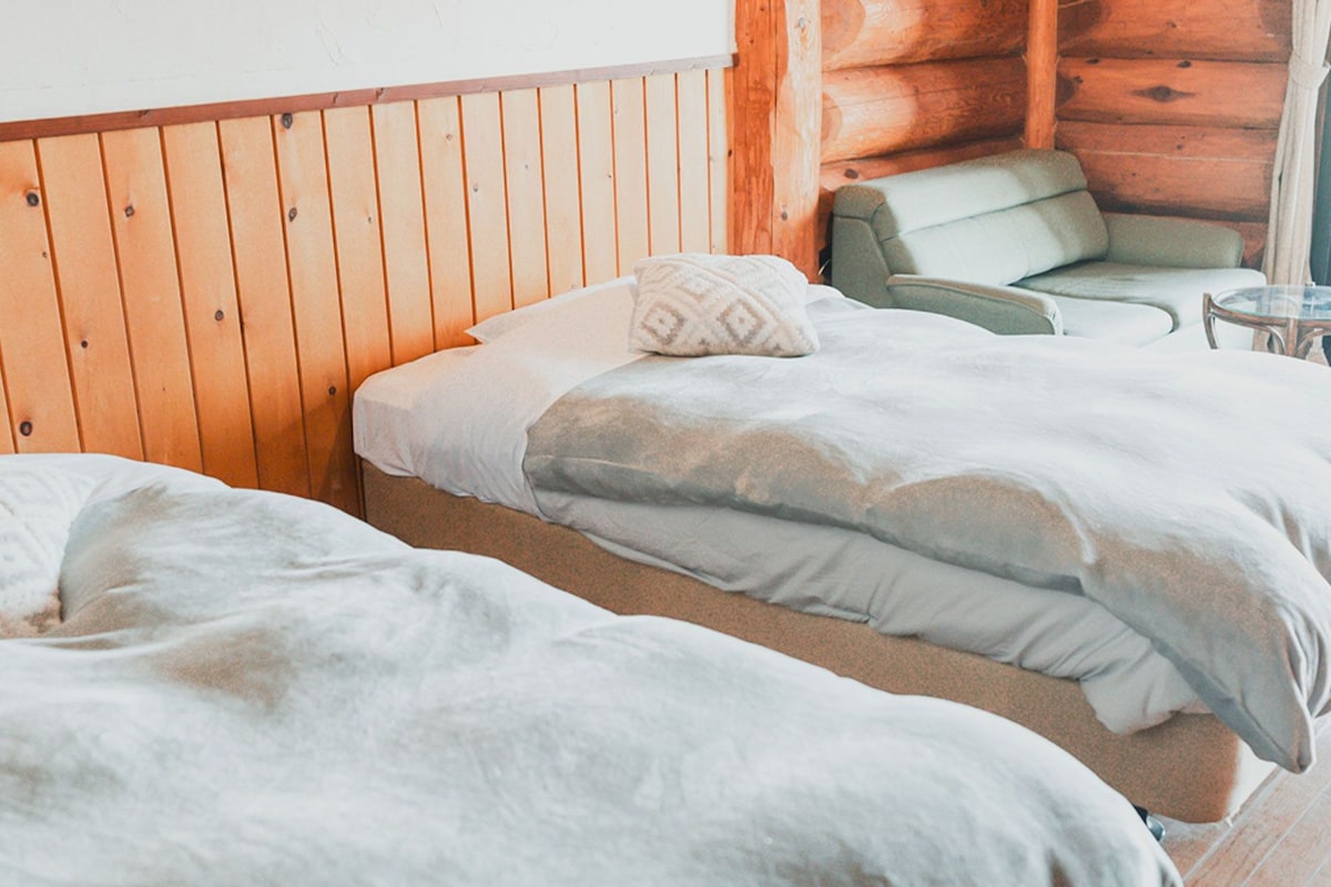 A wooden cabin room with a bed, a chair, and a small table.