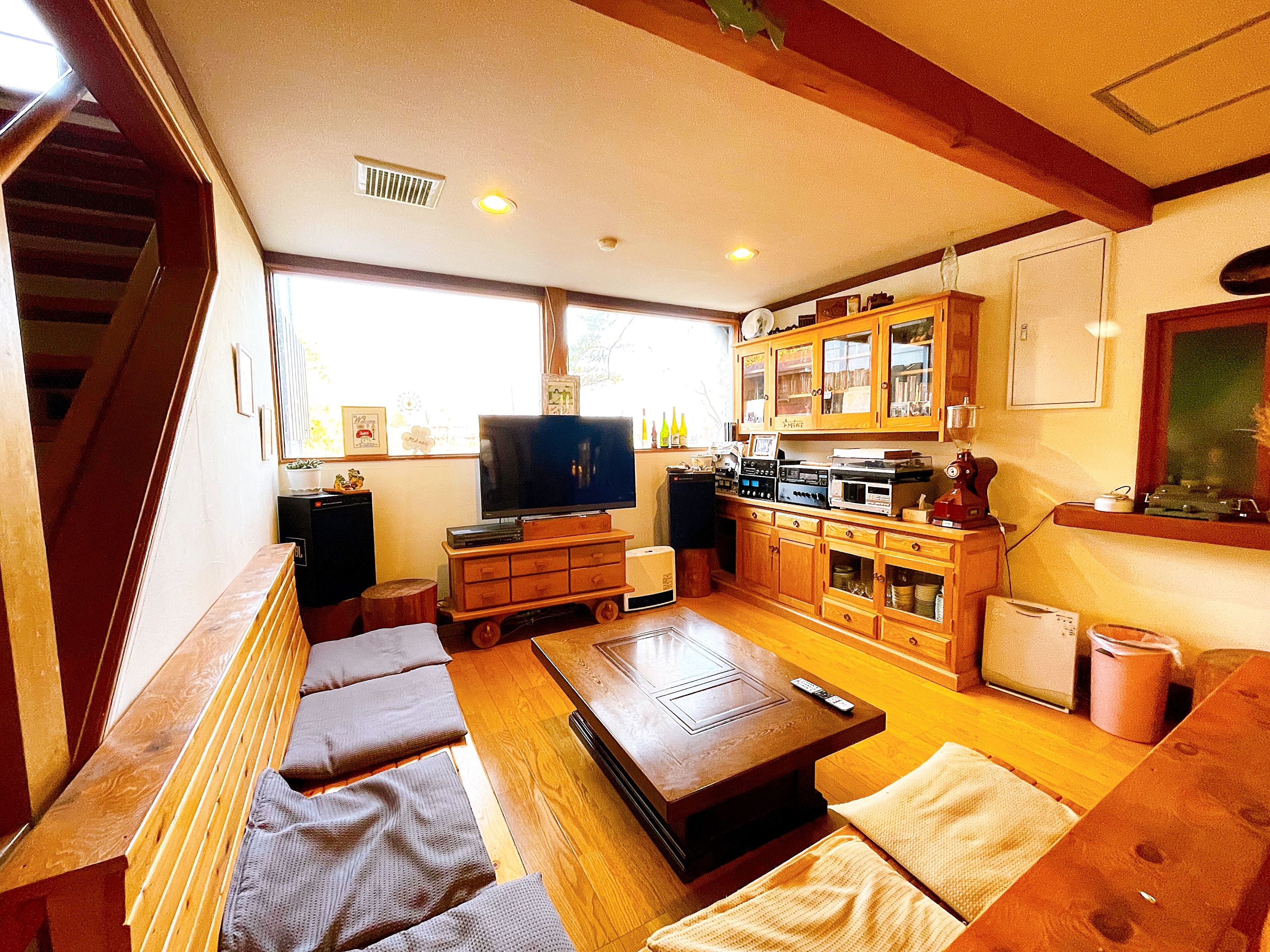 A cozy living room with a wooden bench, a television, and a kitchen area with cabinets and appliances.
