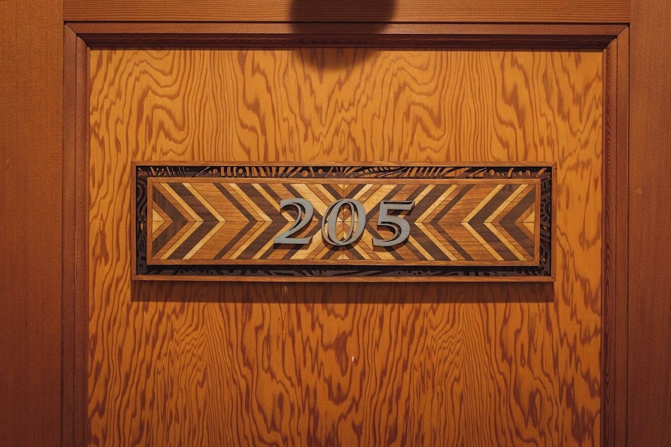 A wooden door with a number plaque displaying '205'.