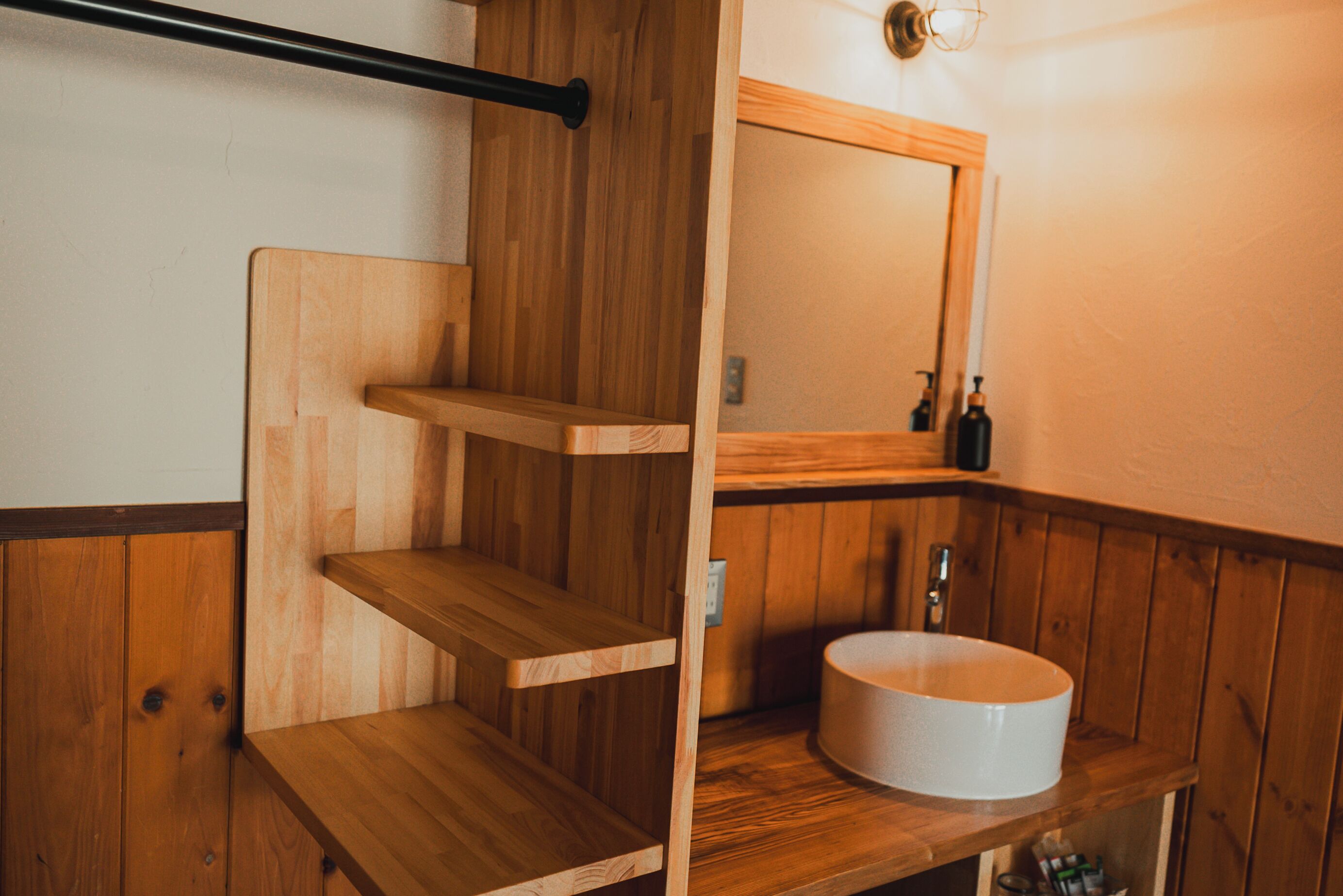 A wooden bathroom with a round sink, a mirror, and a towel rack.