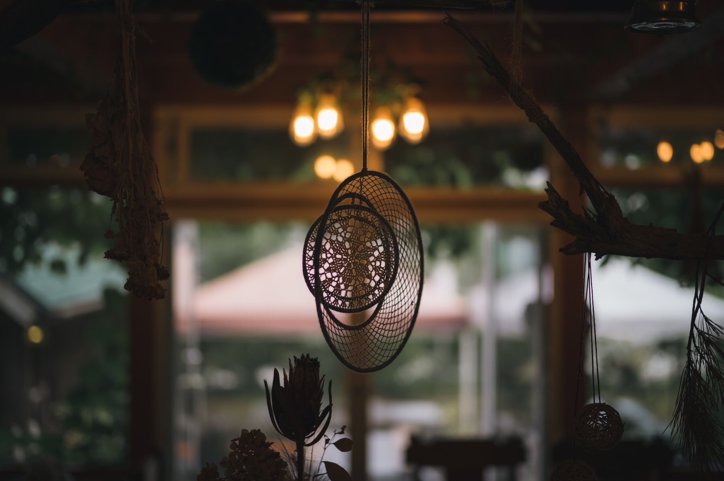 A hanging light fixture with a geometric design, a window with a view of greenery, and a rustic interior.