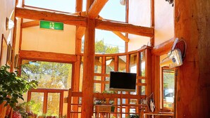 A wooden cabin with a TV, wooden furniture, and large windows. - Hakuba Pension Meteor (Hakuba)