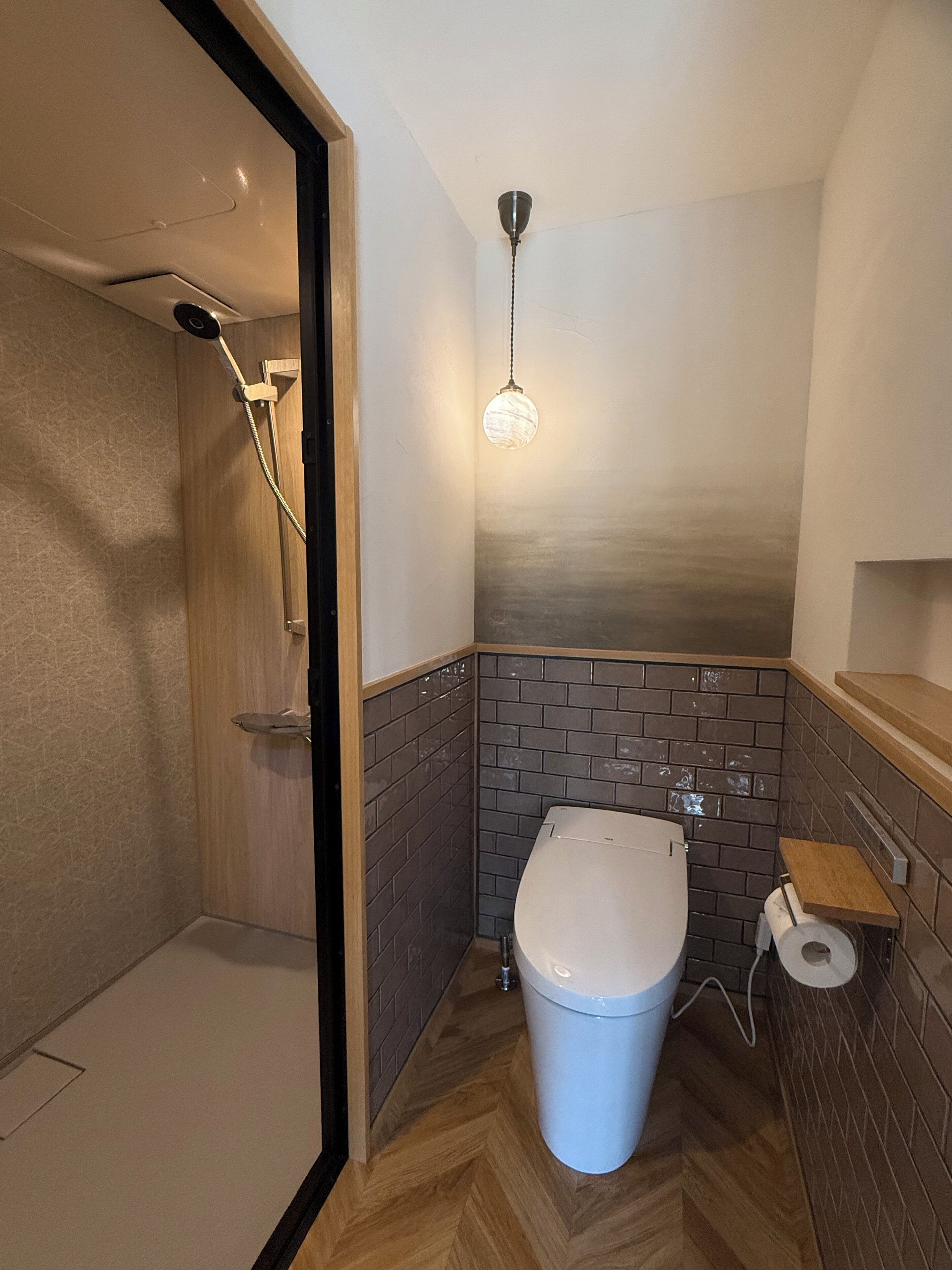 Un baño moderno con ducha, inodoro y una lámpara colgante.