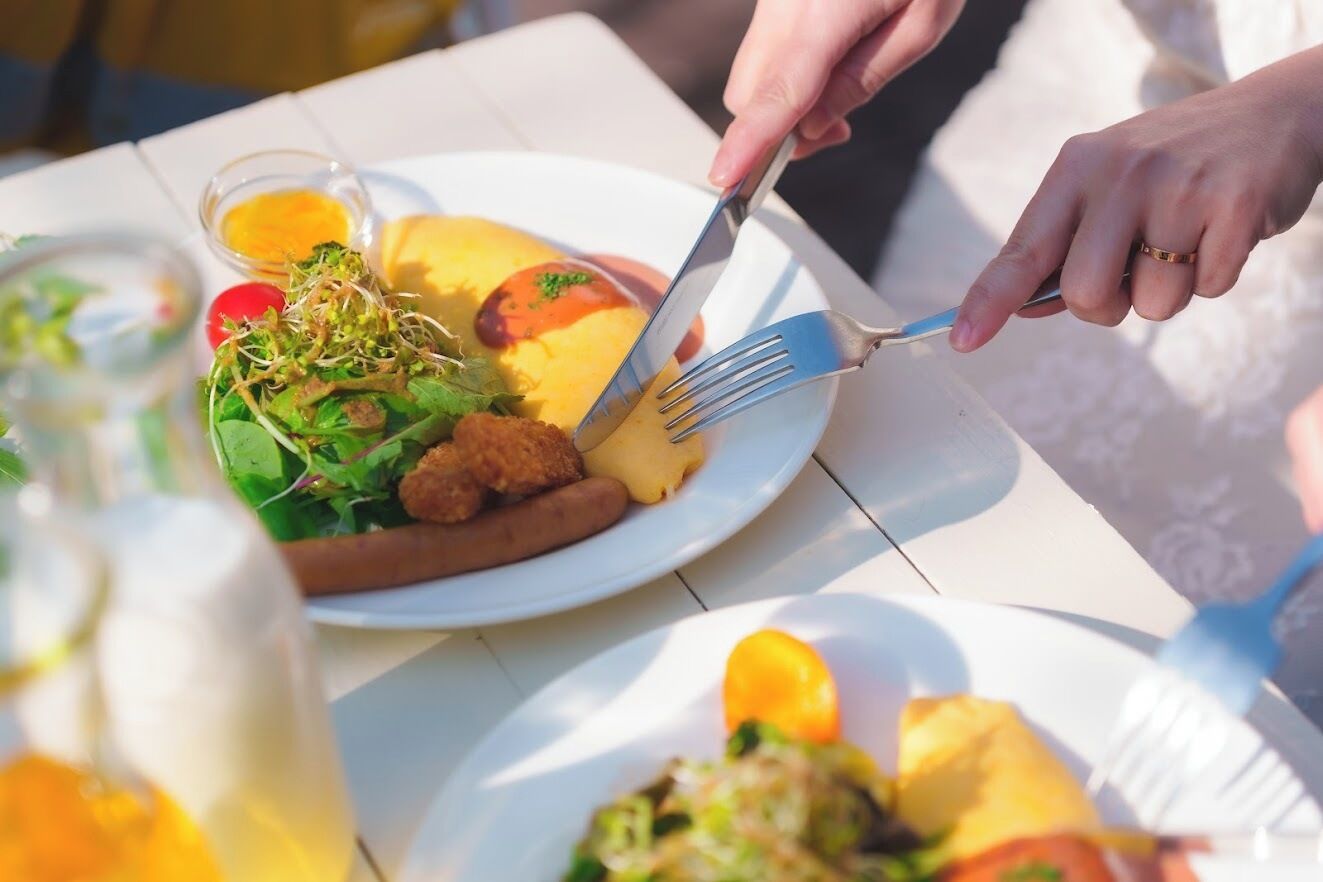A dining table with a plate of food, a fork, and a glass of drink.