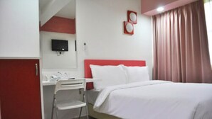Una camera d'albergo con un letto, una scrivania, una sedia, una televisione e una finestra con tende.