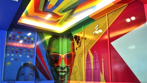 Un interno colorato con un cartello 'WELCOME', un grande murale e un design geometrico del soffitto.