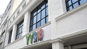 Un hotel con facciata moderna, ampie finestre e un cartello ben visibile con la scritta "YY318 HOTEL".