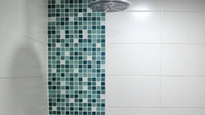 Bagno con doccia, pareti piastrellate e dispenser di sapone.