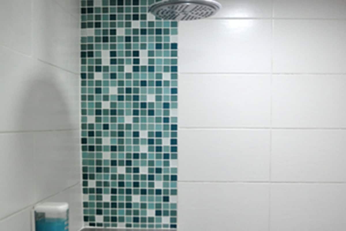 A bathroom with a shower, tiled walls, and a soap dispenser.