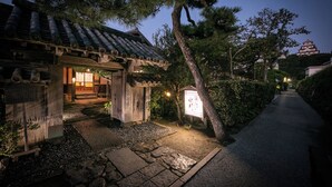 Ein traditionelles japanisches Gebäude mit einem Ziegeldach, einem Kiesweg und einer kleinen, schreinähnlichen Konstruktion.