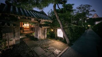 A traditional Japanese building with a tiled roof, stone pathway, and a signboard.