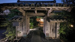 Ein traditionelles hölzernes Torii-Tor, das zu einem Gebäude mit einem Ziegeldach führt.