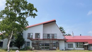 A two-story building with a red roof and large windows. - Mashuko Youth Hostel (Teshikaga)