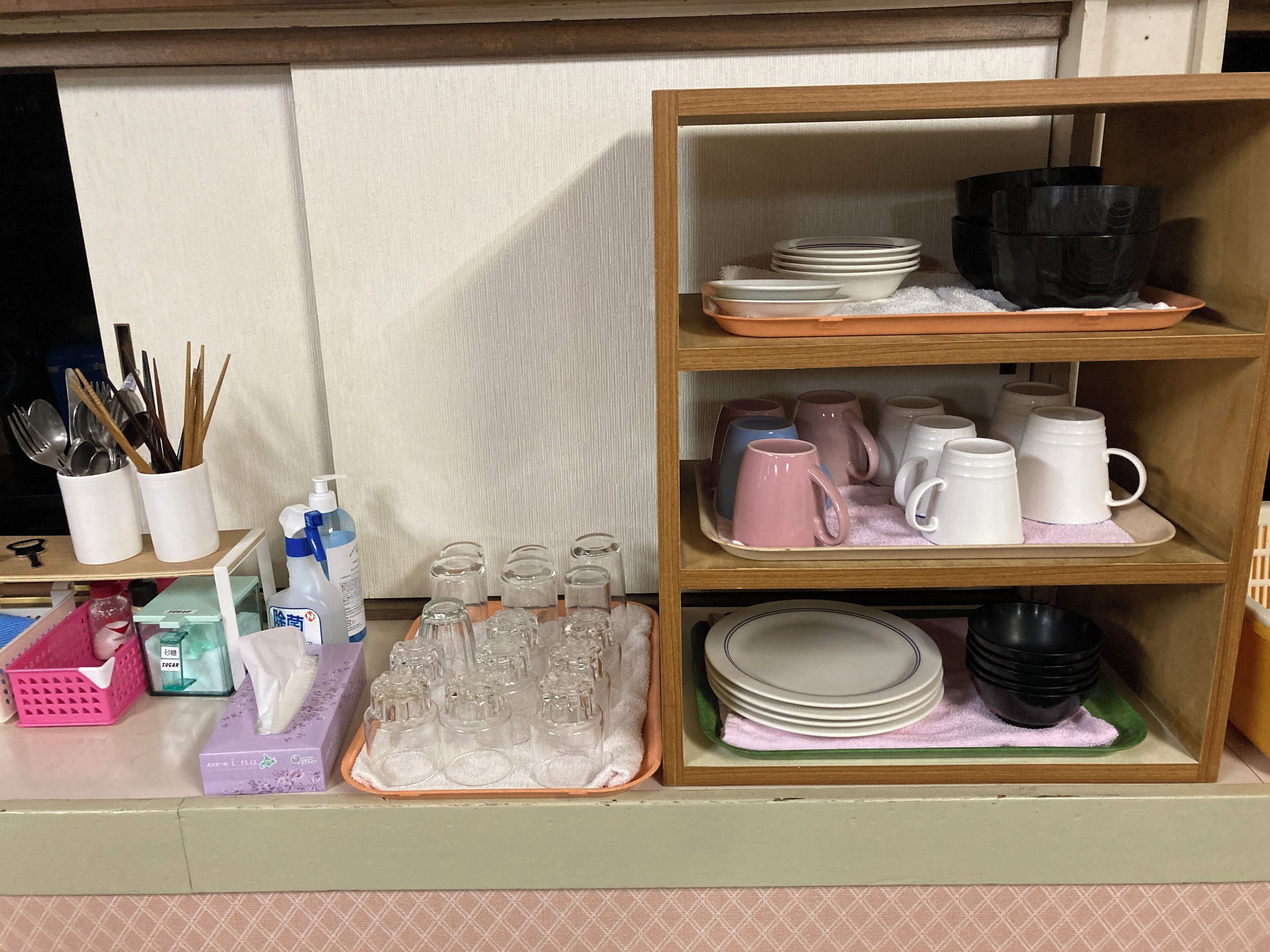 A kitchen area with shelves holding dishes, glasses, and utensils.