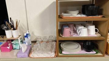 A kitchen area with shelves holding dishes, glasses, and utensils.