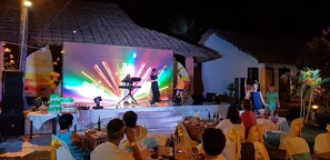 An outdoor event with a stage, tables, and chairs set up for an audience.
