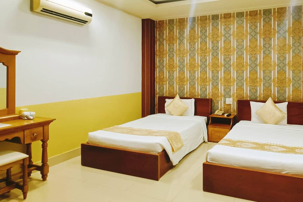 A hotel room with two single beds, a wooden desk with a chair, a nightstand, and a mirror.